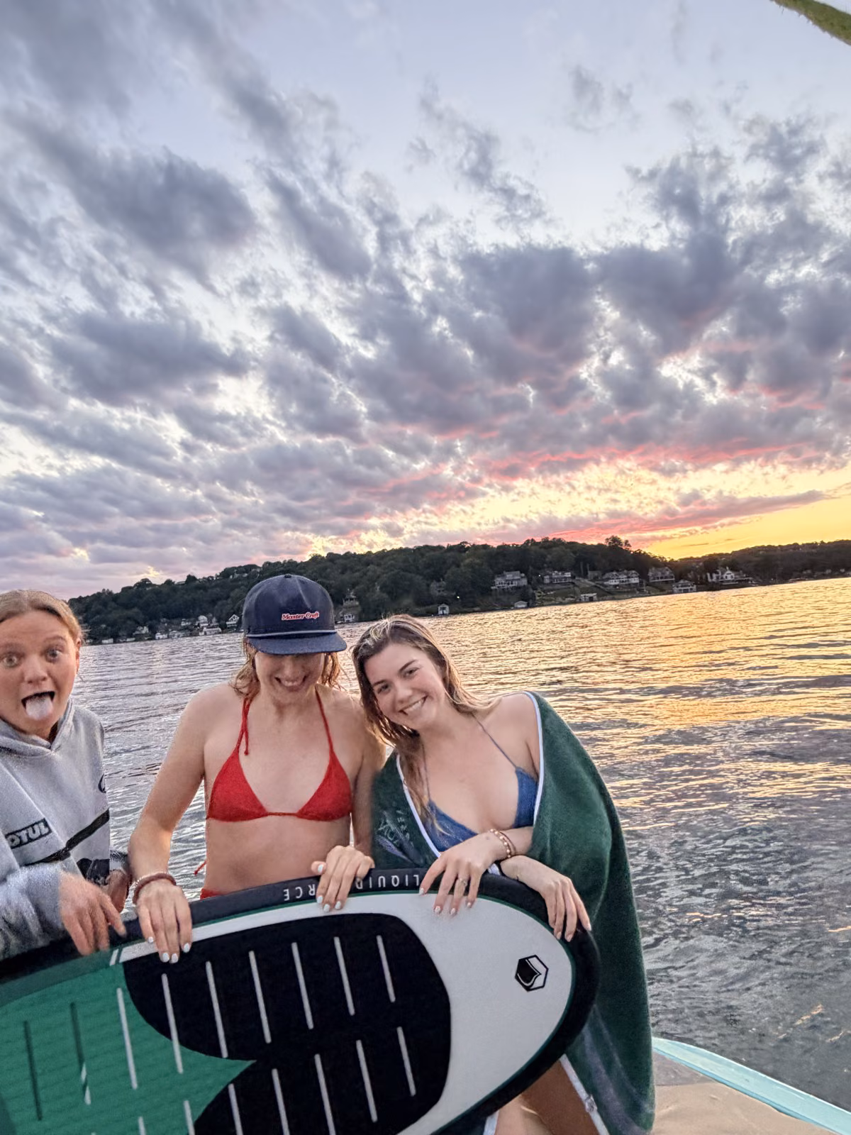 Invitados de Wake Club con una tabla de wakesurf al atardecer en Lake Hopatcong