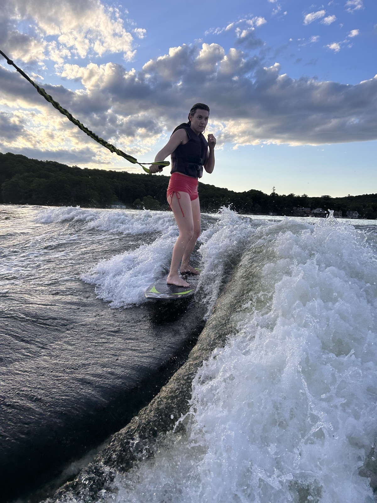 A young rider wakesurfing the wave behind the boat on Lake Hopatcong